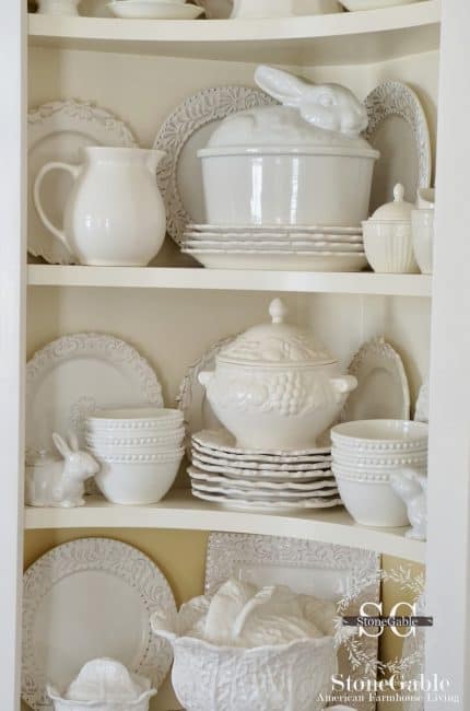 A white cabinet with white dishes in it.