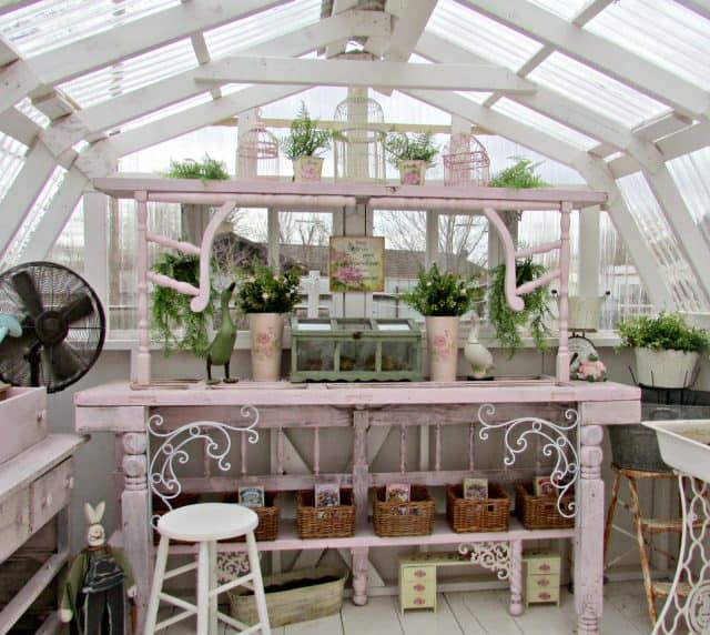 A garden room with a pink wooden desk and a vignette on it.