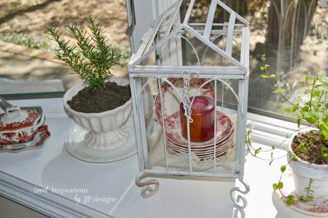 White birdcage with plates and a candle inside it.