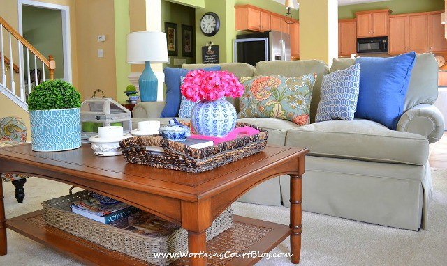 A wooden coffee table styled with a tray and boxwood plants.