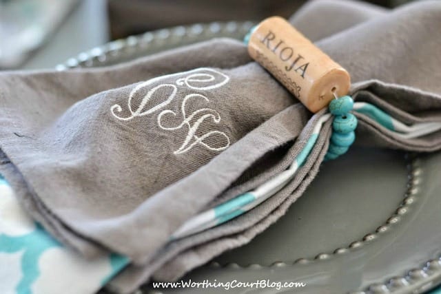 Grey napkins with a turquoise beaded string and wine cork.