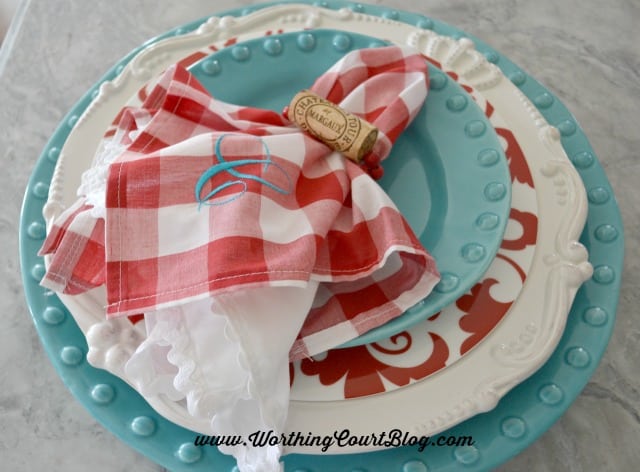 The cork napkin holder with a red and white napkin.