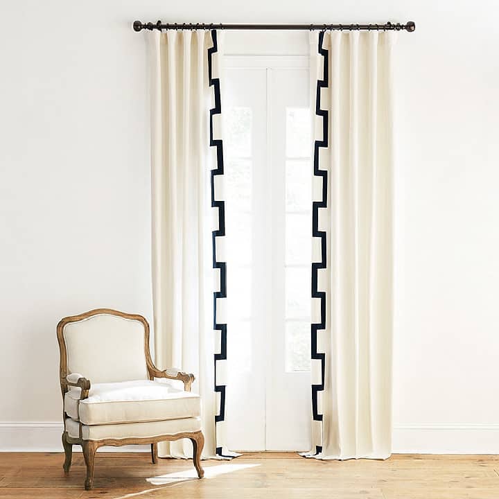 white curtains embellished with grosgrain ribbon in a fretwork pattern