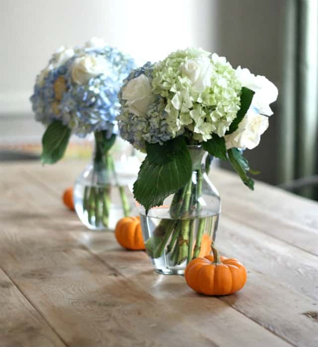 Ease into fall decorating by mixing mini pumpkins with summer flowers that are still blooming.