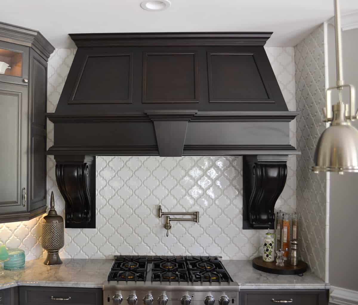 huge custom black hood above a Viking range with a white quadrifoil tile backsplash