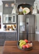 stainless steel double door fridge in a bank of custom gray kitchen cabinets