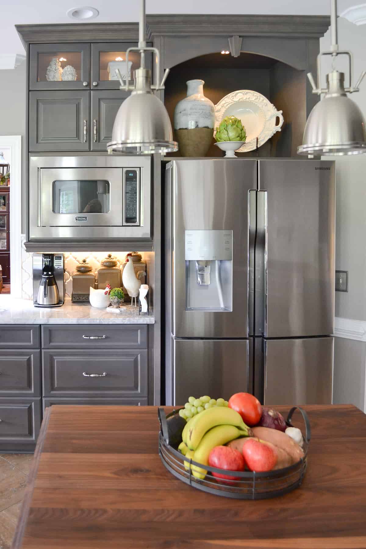 stainless steel double door fridge in a bank of custom gray kitchen cabinets