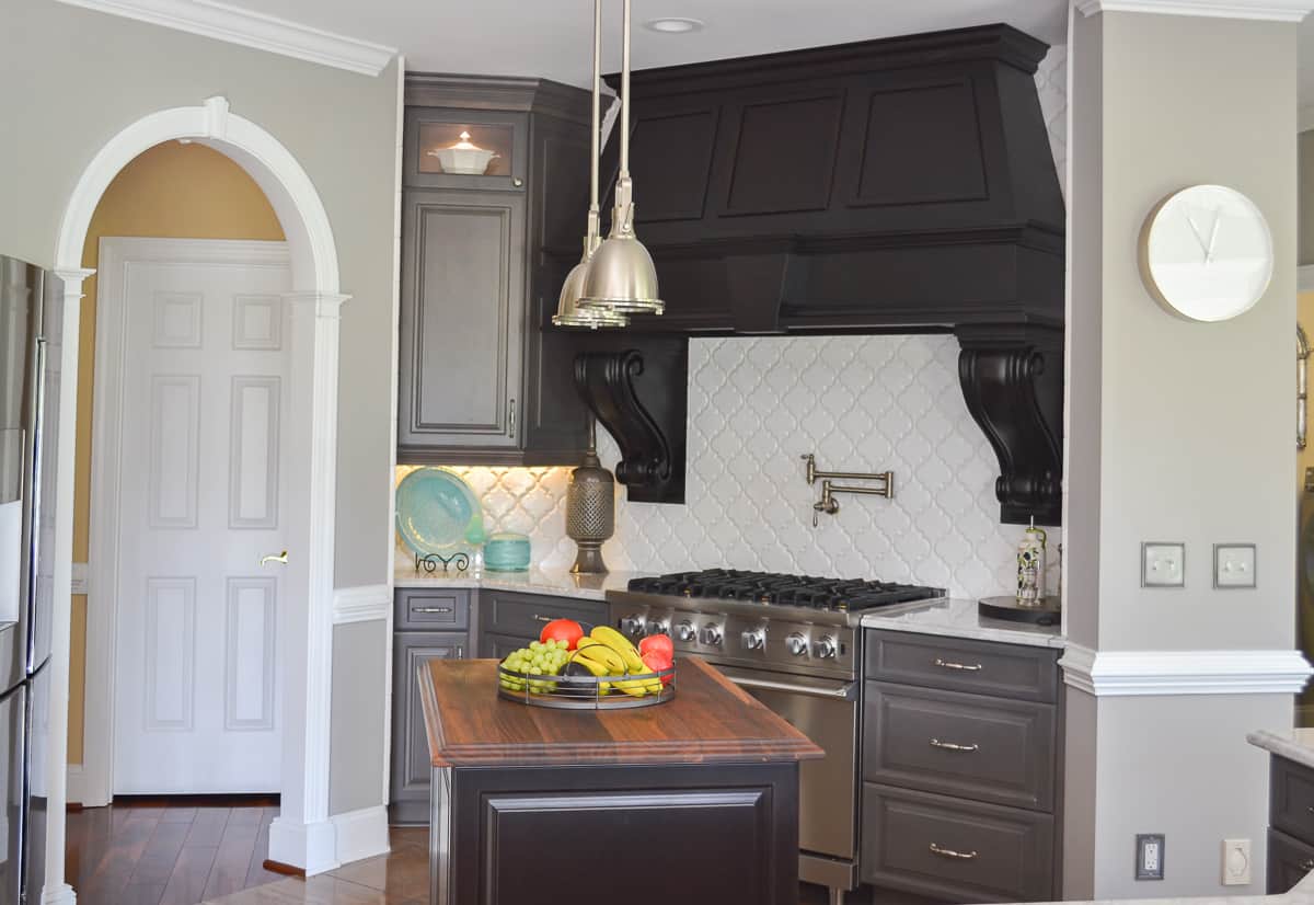 huge custom black hood above a Viking range with a white quadrifoil tile backsplash