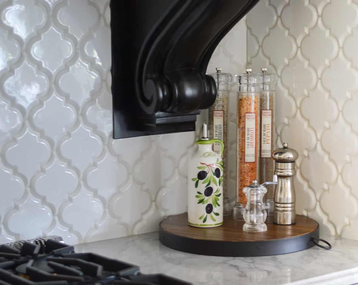 bottles of flavored oils on a round wood tray on a kitchen counter