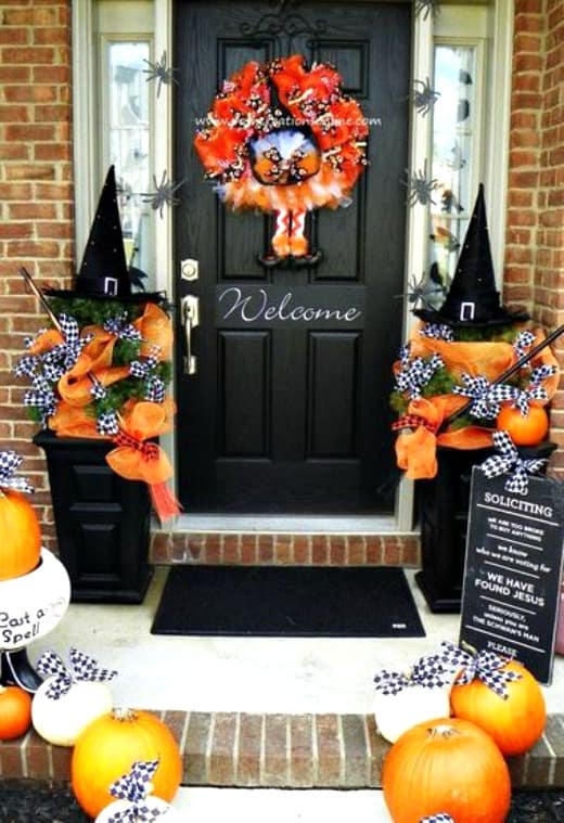 Black witches hats flank the front door of this home with pumpkins as well.