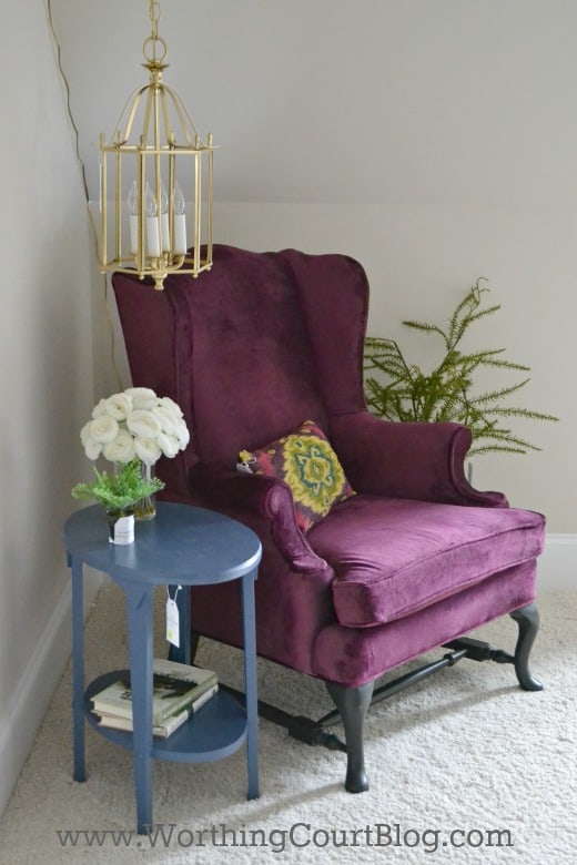 A cozy ready nook with a lantern suspended from a chain.