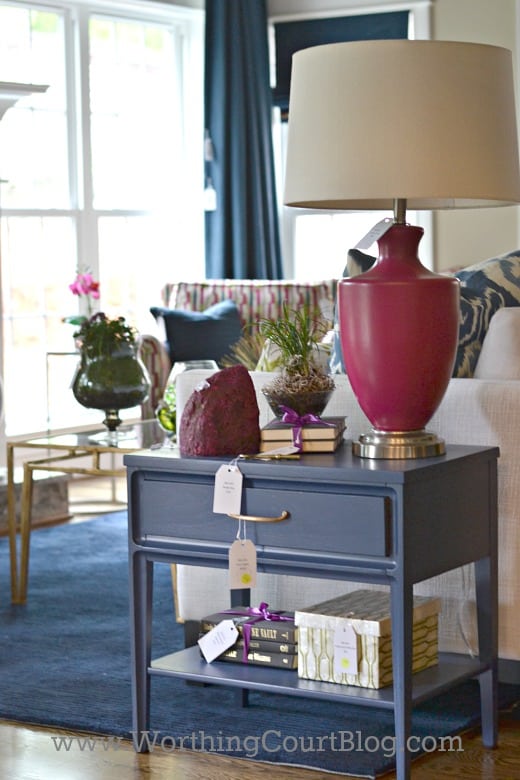 A small blue end table with a red lamp on it.