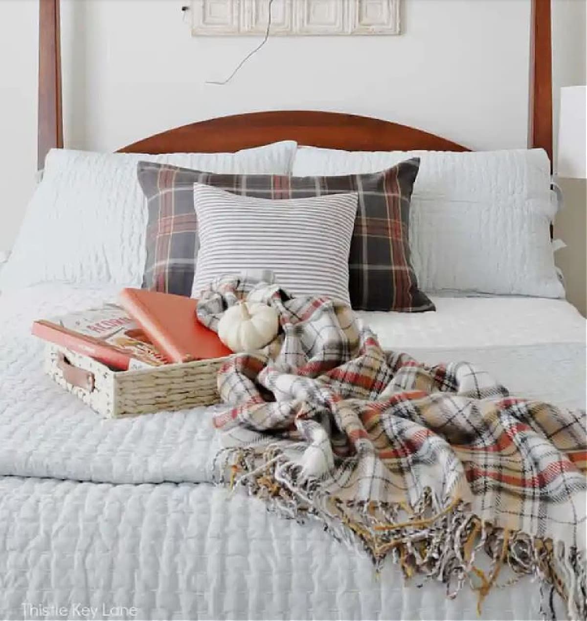 Plaid fall decor with a plaid throw on a white bed with fall pillows