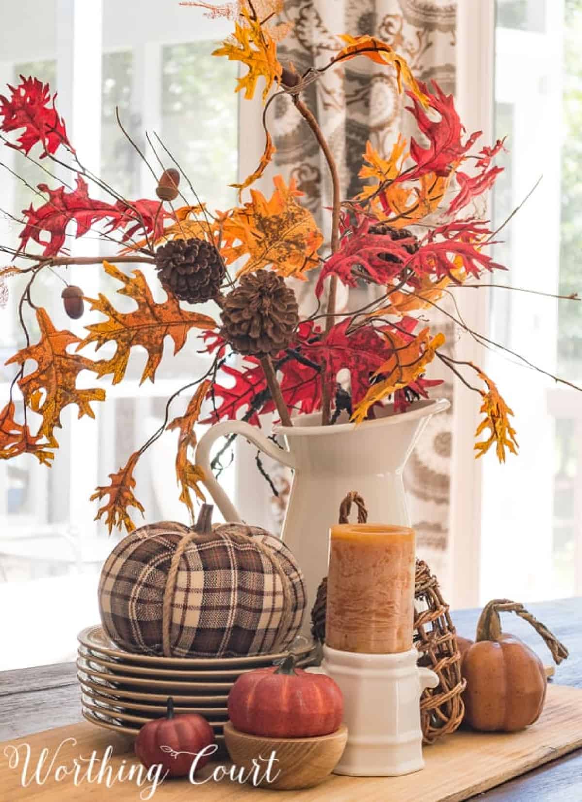 fall centeripece with fall colored foliage a plaid pumpkin and fall candle