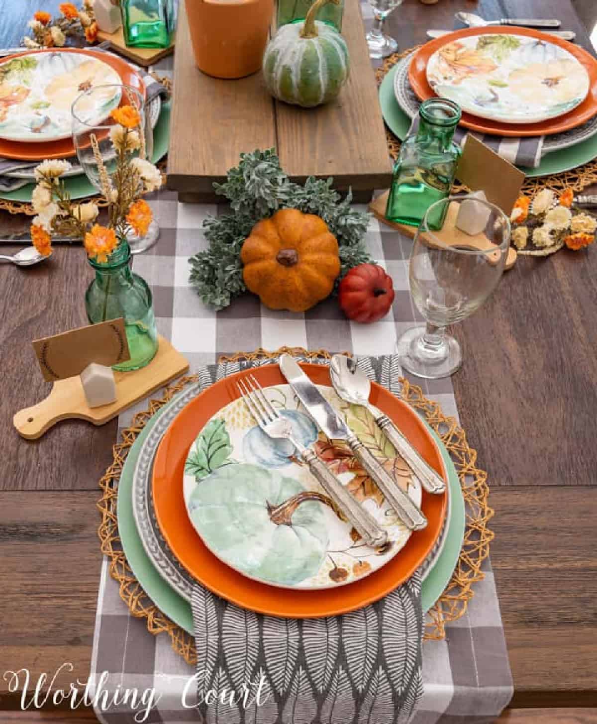 fall table setting with stacked falled colored dishes on a buffalo check plaid gray and white runner