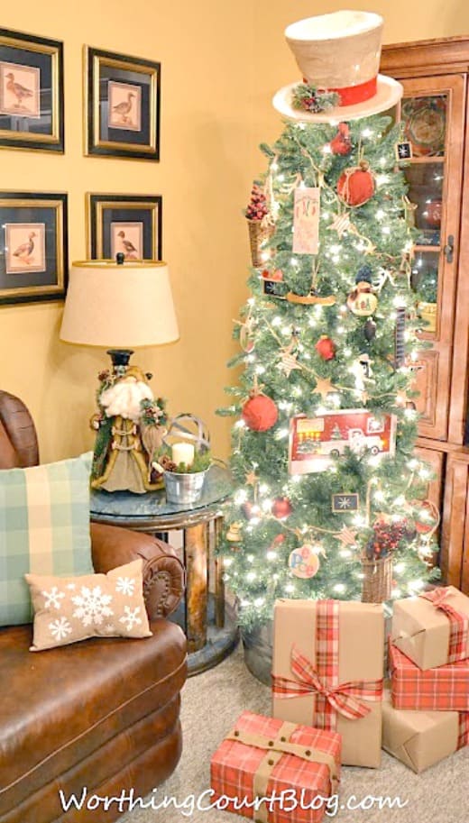 A rustic Christmas tree topped with a burlap snowman hat, diy red ticking and burlap garland and diy ornaments.