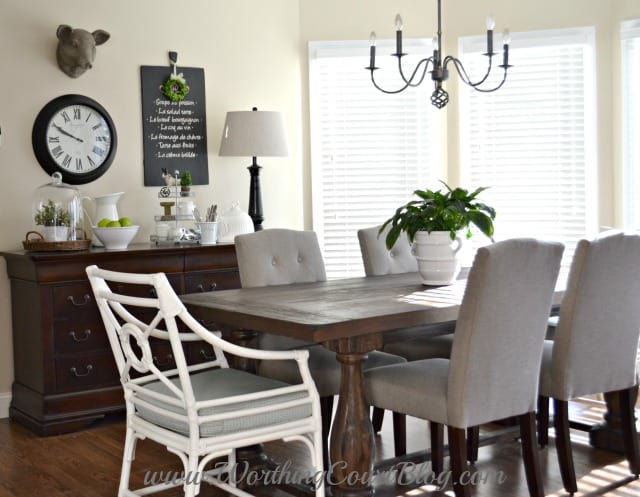 A wooden kitchen table with fabric chairs and a chandelier above the table.