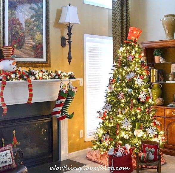 A large decorated Christmas tree in the corner of the room beside the fireplace.