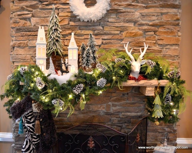 Beautifully decorated Christmas mantel with antlers and a Christmas village.