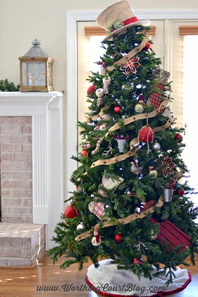 Rustic Christmas Tree completely decorated beside the fireplace.