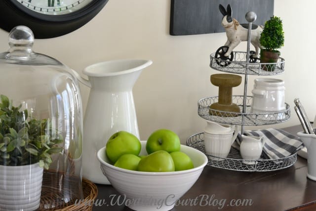 There is a white bowl filled with apples on the dresser.