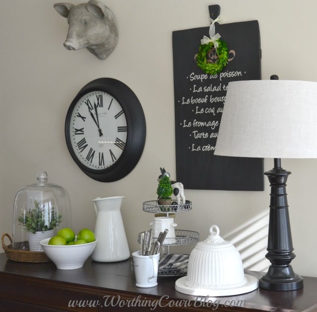 Farmhouse kitchen vignette with a glass cloche and a small lamp on the table.