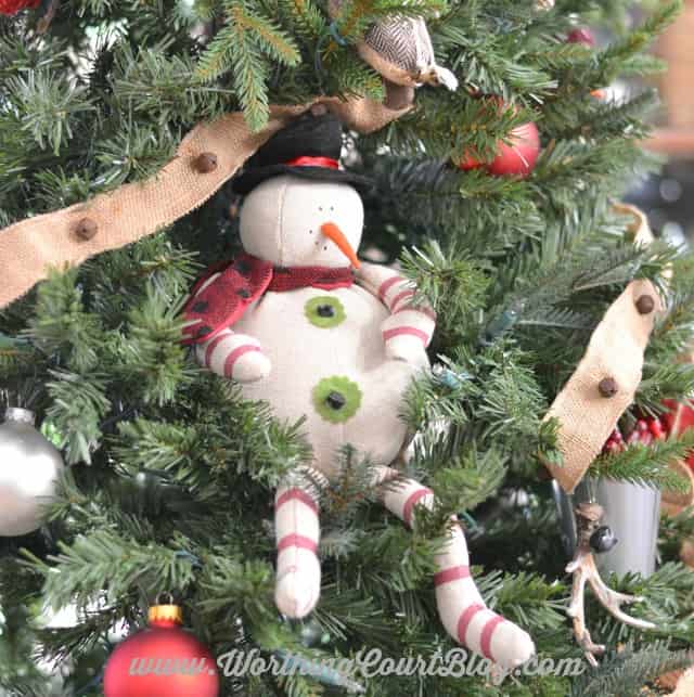 A snowman that is sitting in the Christmas treee.