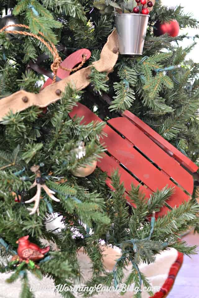 A red wooden sleigh towards the bottom of the Christmas tree.