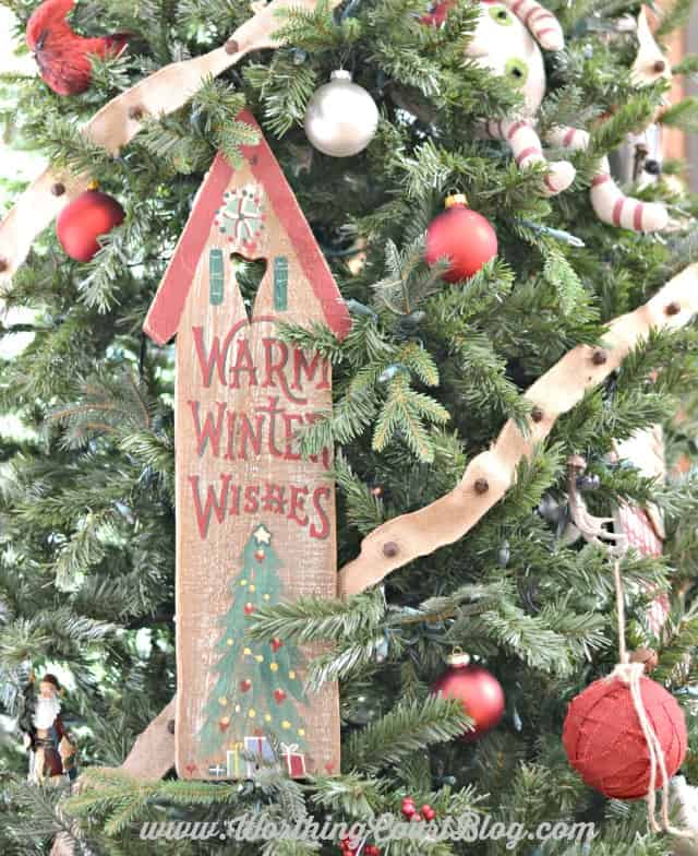 A wooden door plaque wired to a Christmas tree with green floral wire.