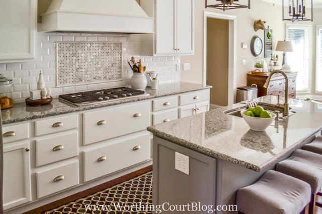 A bowl of green apples are on the kitchen island.