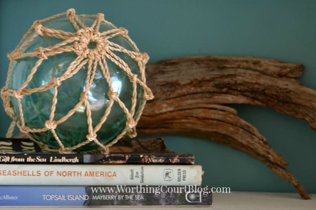 A glass orb wrapped in rope beside driftwood.