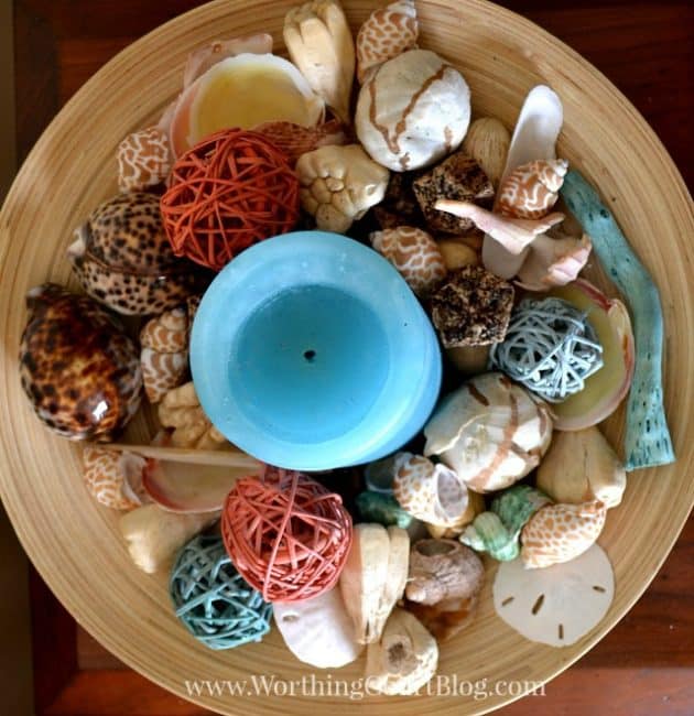 Birdseye view of a bamboo bowl filled with shells, straw orbs and straw orbs.