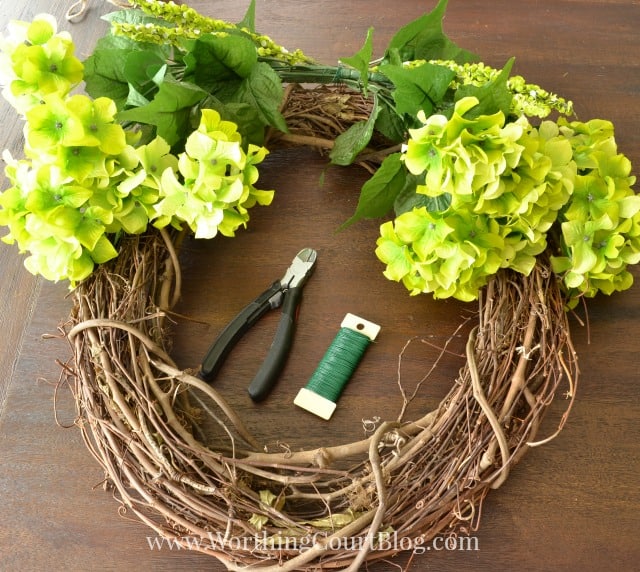 Attaching the florals and greenery to the grapevine wreath.