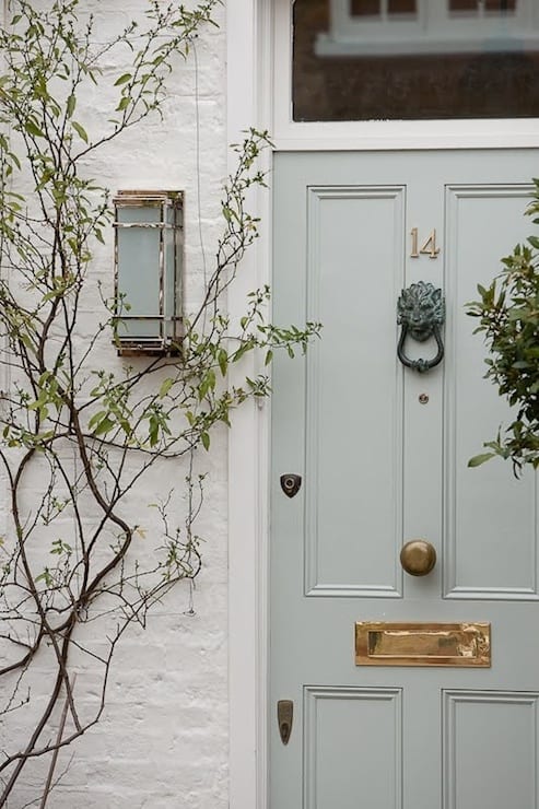 A beautiful grey-green painted front door on a white brick home.