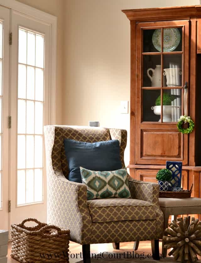 A corner armchair with throw pillows on it.