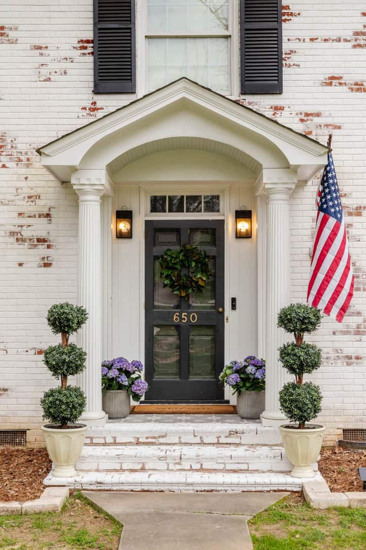front porch on a white brick house with a black door
