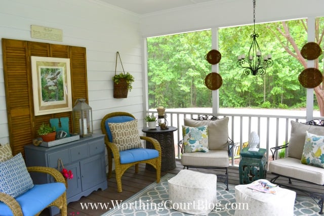 There is a rug in the middle of the porch with chairs around it.