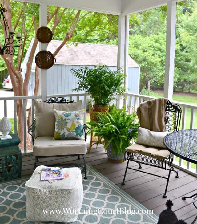 There are potted plants in the corner of the porch.