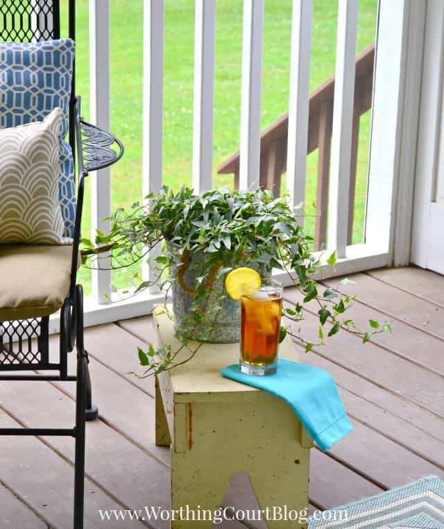 A small stool is beside the chairs on the porch.