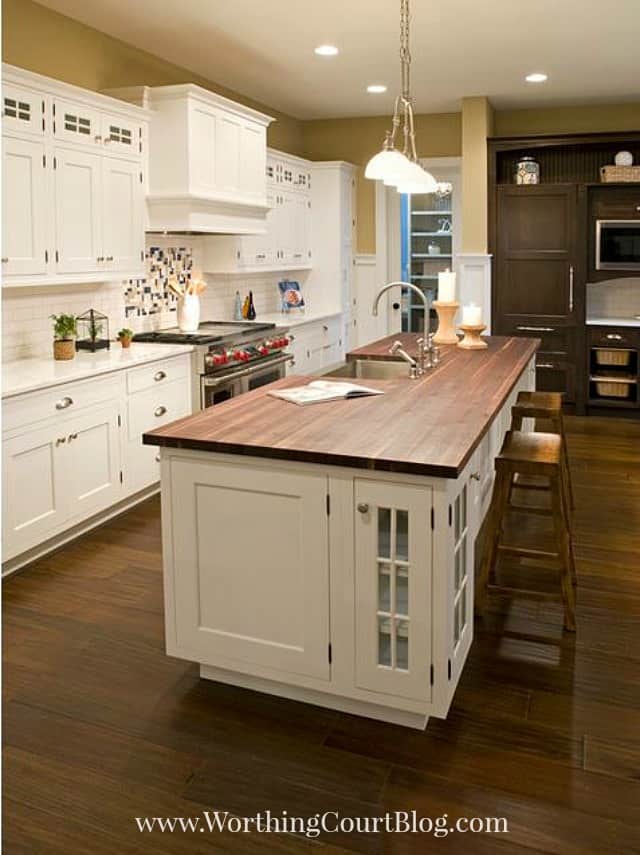 A white kitchen island with a wood top.