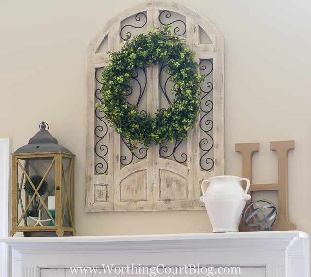 The fireplace mantel with a grapevine wreath above it.