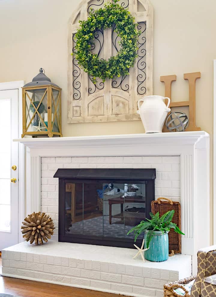 White painted brick fireplace flanked by french doors and arm chairs.