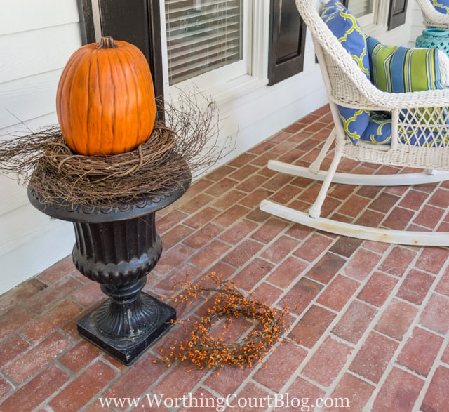 Placing the pumpkin on top of the grapevine wreath on the urn.