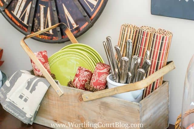 A wooden picnic basket filled with plates, cutlery, and napkins for a fall picnic.