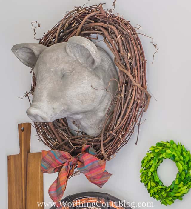 Faux pig head dressed up for fall with a twig wreath and a fall ribbon bow tie