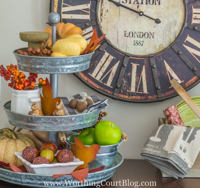 Up close of the tiered galvanized tray, filled with pumpkins, small squirrel figurines, acorns and apples.