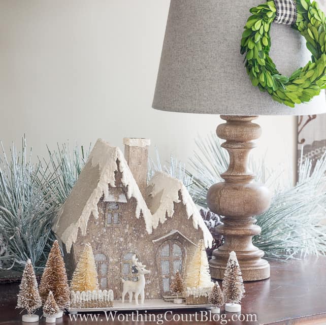 A glittery Christmas house is on the sideboard.