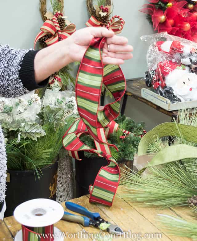 Adding a green and red bow to the wreath.