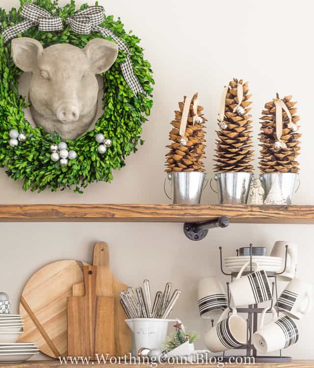 Pine cones are sitting in small silver buckets with bells.