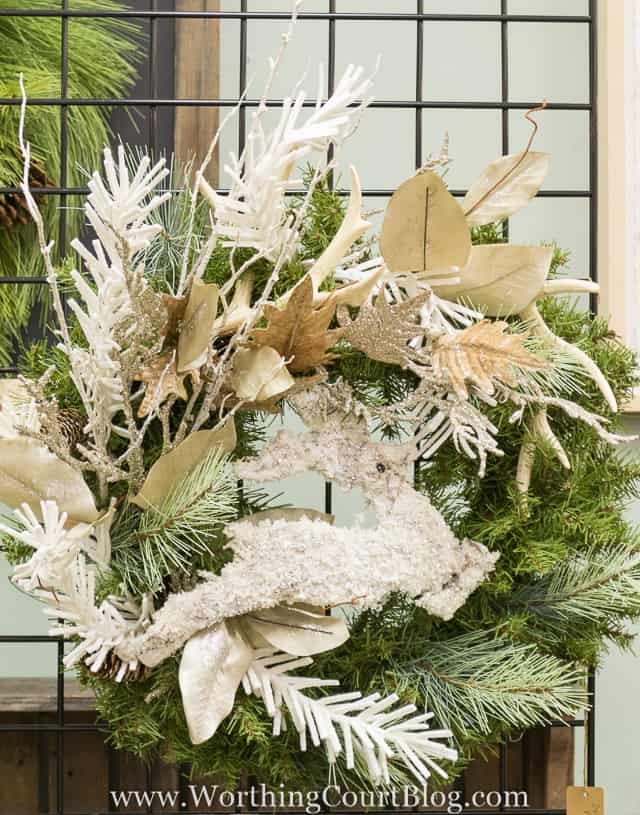 A wreath with a glittery deer on it surrounded by flocked leaves.